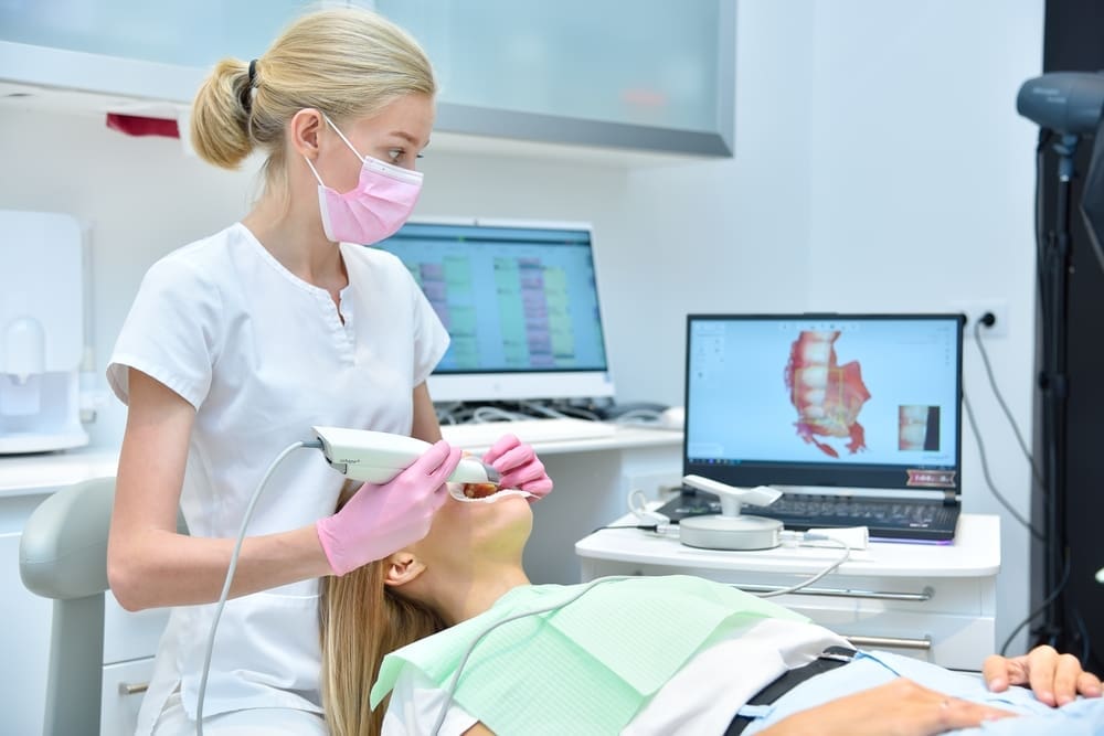 Orthodontist scaning patient with dental intraoral scanner and controls process on laptop screen. Prosthodontics and stomatology concept.
